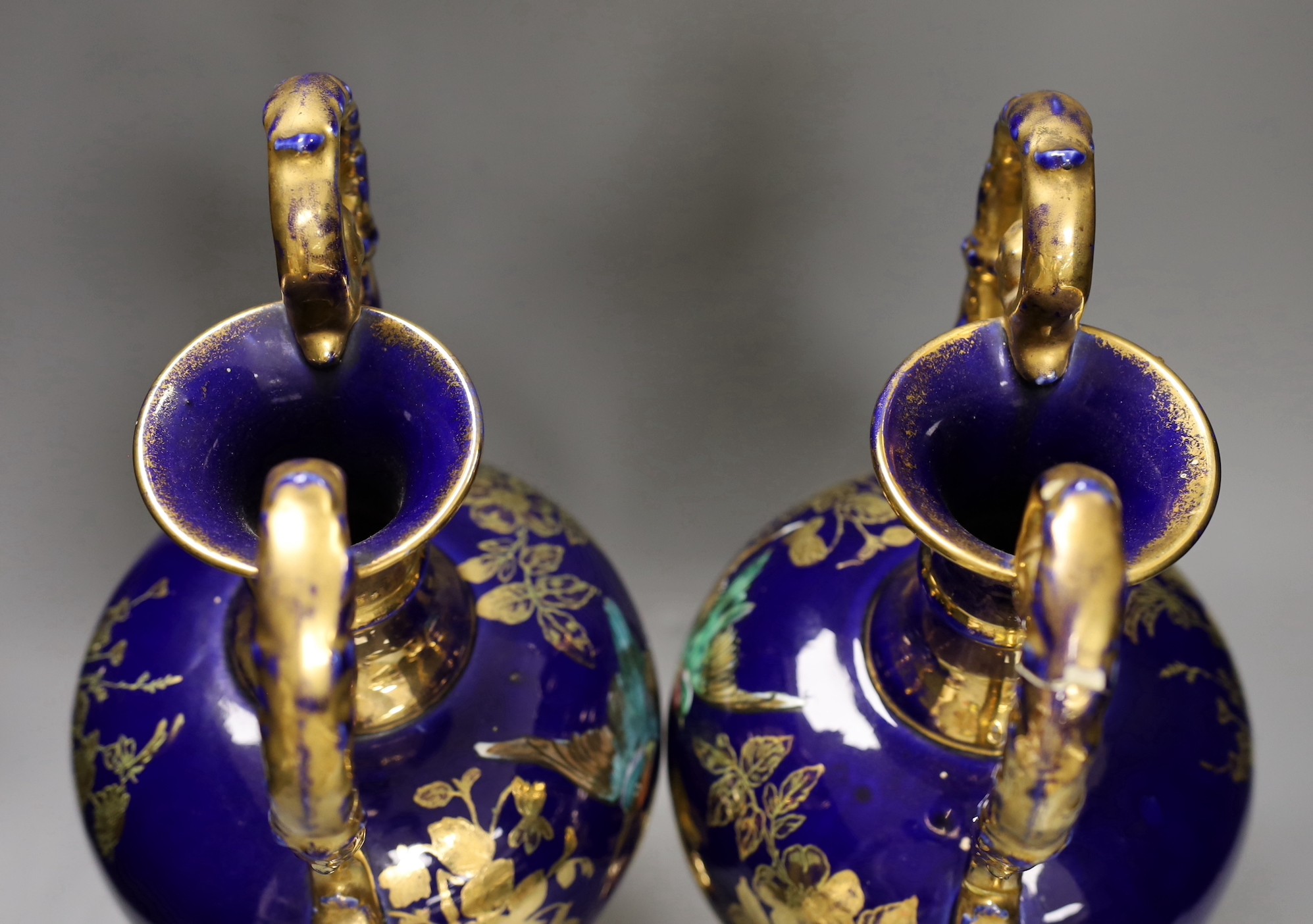 A pair of blue painted two-handled gilt pottery vases with birds amongst ornate gilt decoration. 41cm high